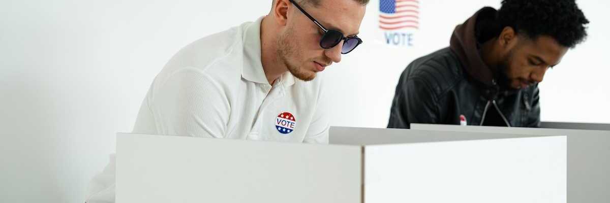 White man and black man in adjacent voting booths, voting in US election