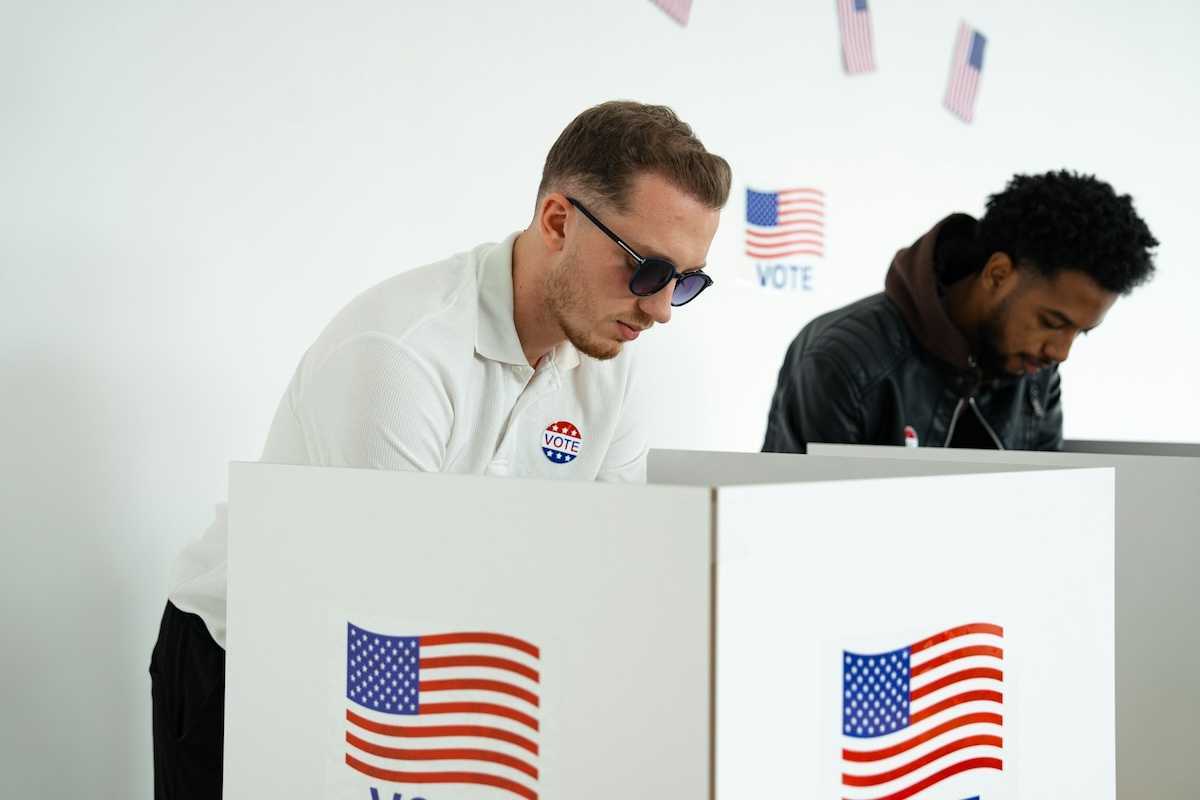 White man and black man in adjacent voting booths, voting in US election