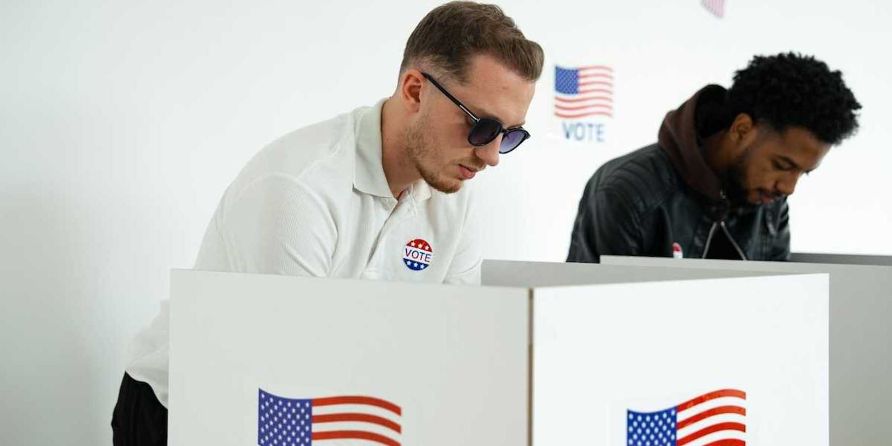 White man and black man in adjacent voting booths, voting in US election