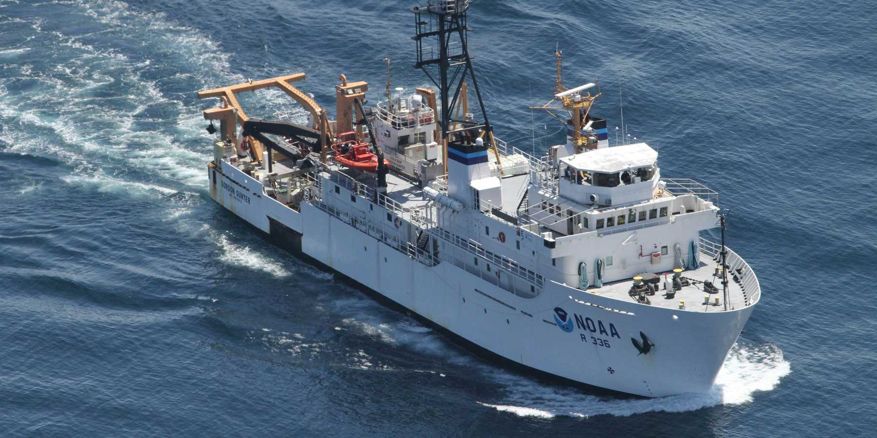 white NOAA research ship travelling during daytime.