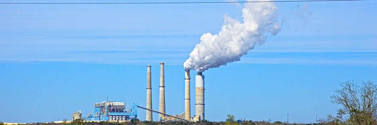 white smoke coming out from power plant on a green hill.