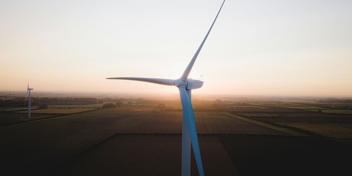 White wind turbine on brown field during daytime.