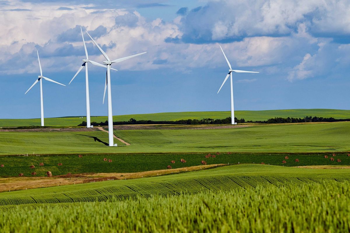 White wind turbines in the midst of green farm fields