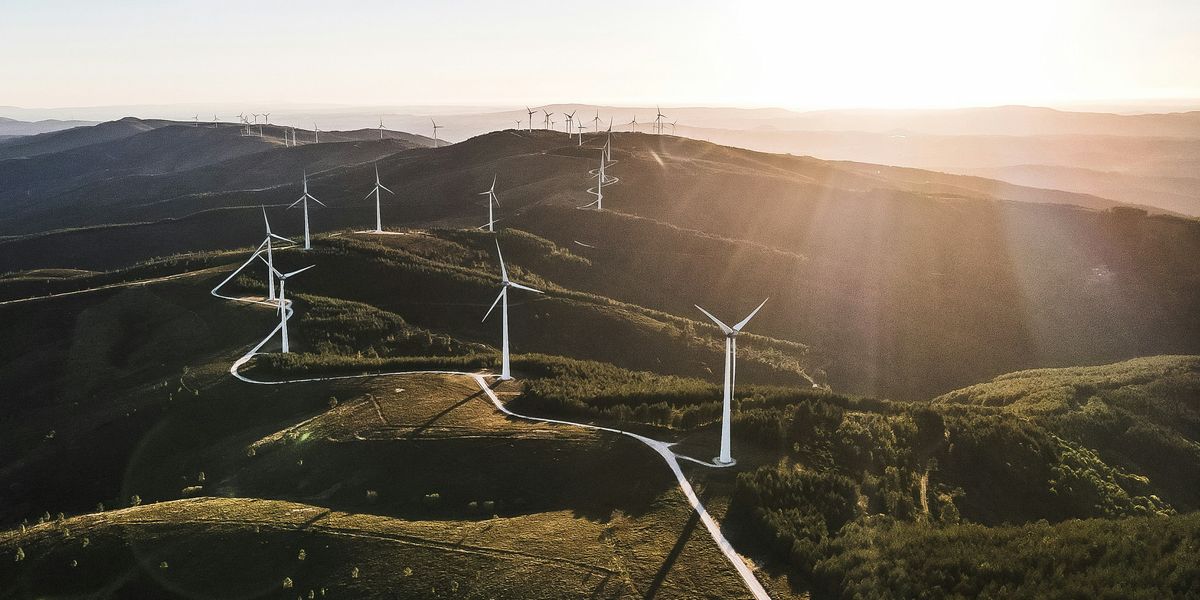 white wind turbines on green grassy hills during daytime.