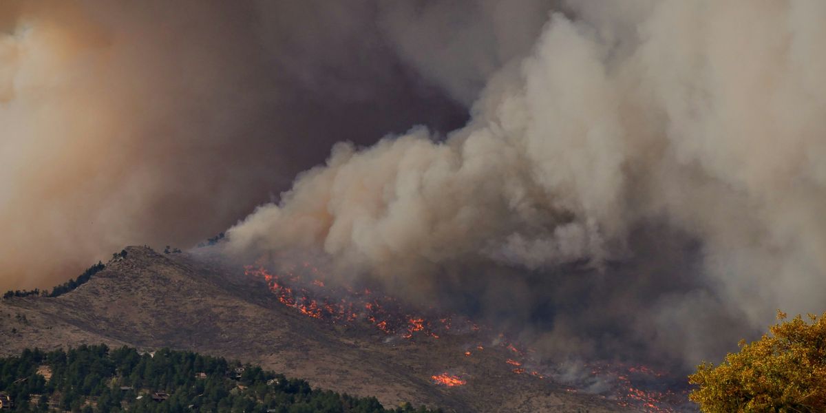 Wildfire on a hill with billowing smoke.