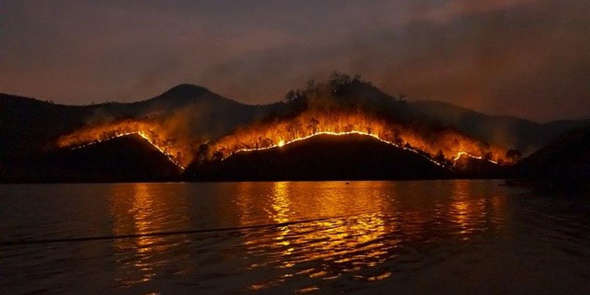 Wildfire spread over a ridge in front of a lake