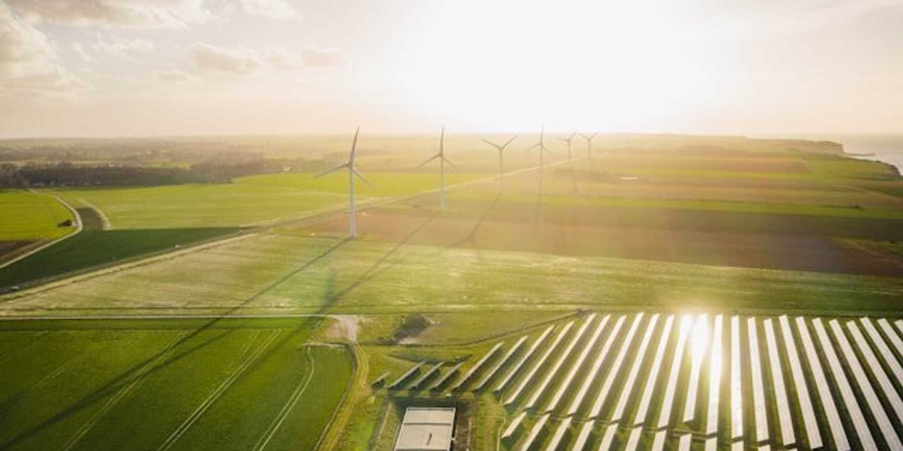 Wind turbines and solar energy panels set in farmland.