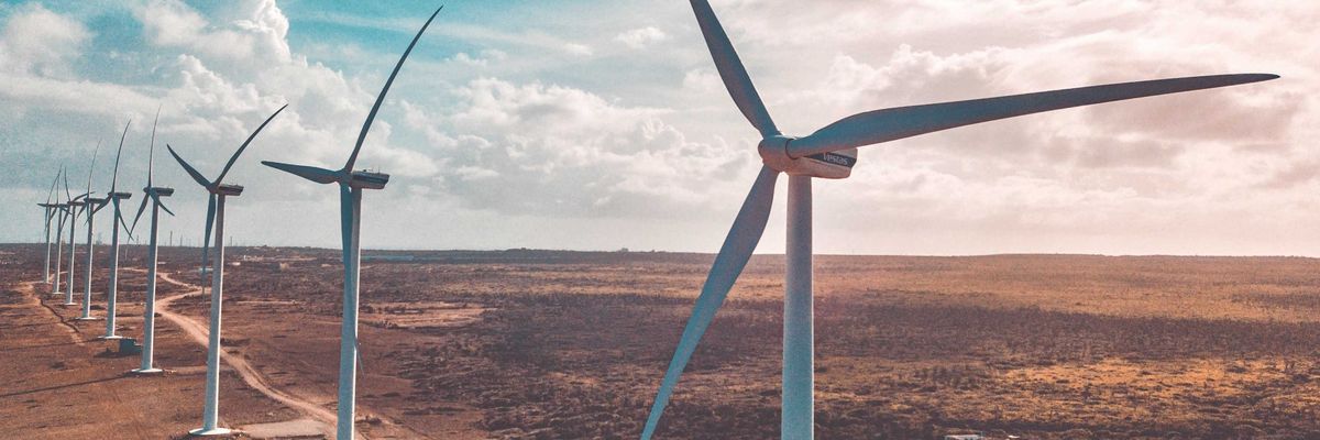 wind turbines in a row in a dry environment under white clouds and blue sky during daytime