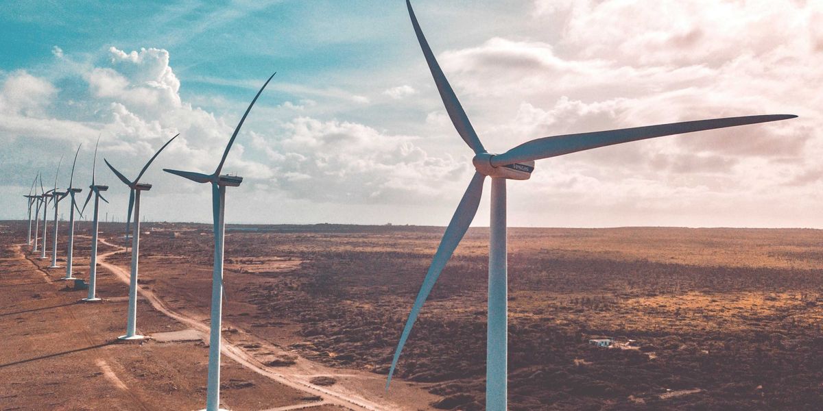 wind turbines in a row in a dry environment under white clouds and blue sky during daytime