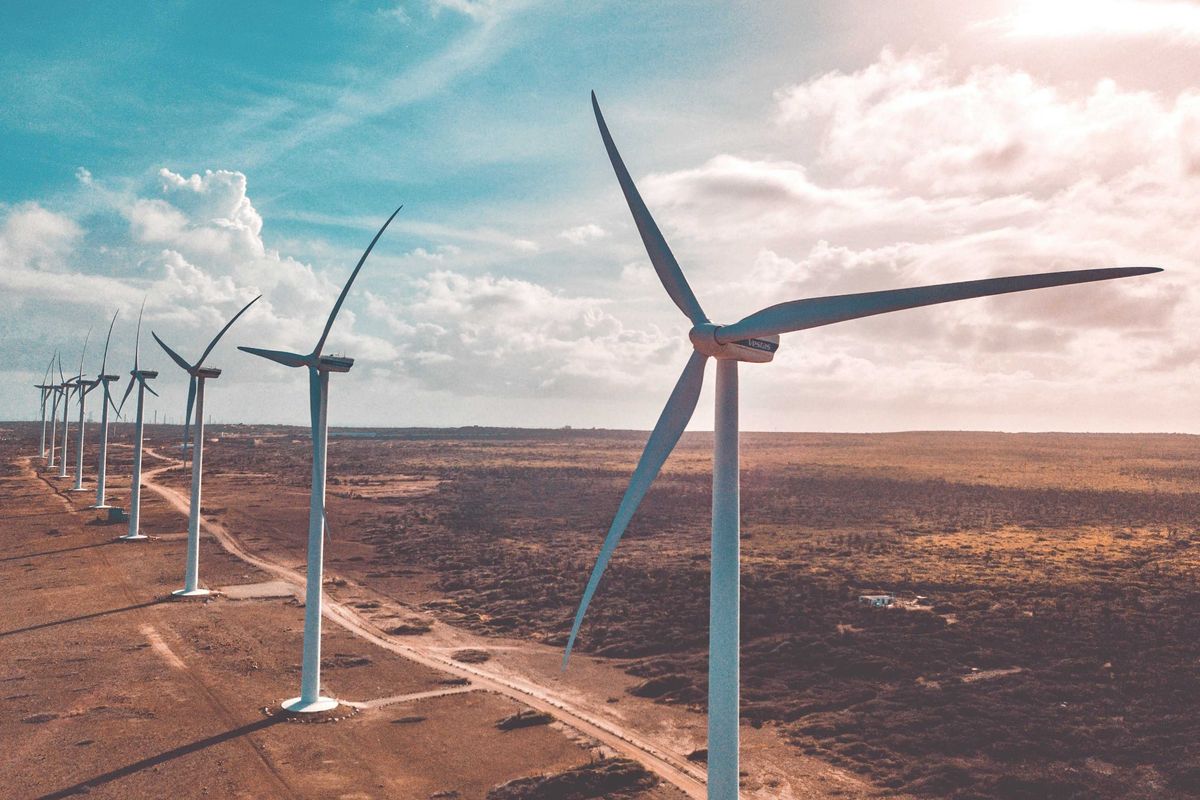 wind turbines in a row in a dry environment under white clouds and blue sky during daytime