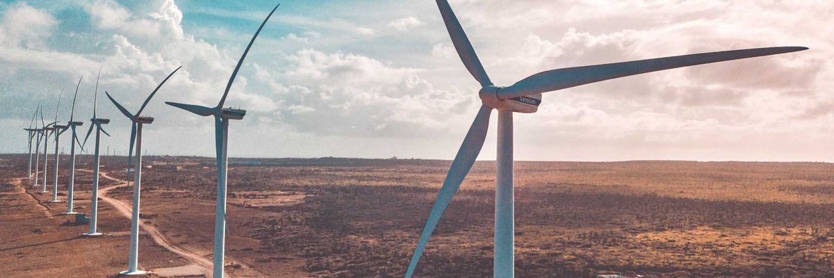 wind turbines on brown sand under white clouds and blue sky during daytime