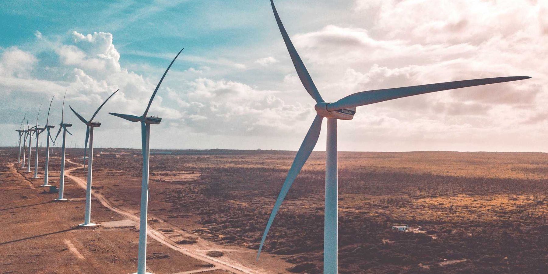 wind turbines on brown sand under white clouds and blue sky during daytime