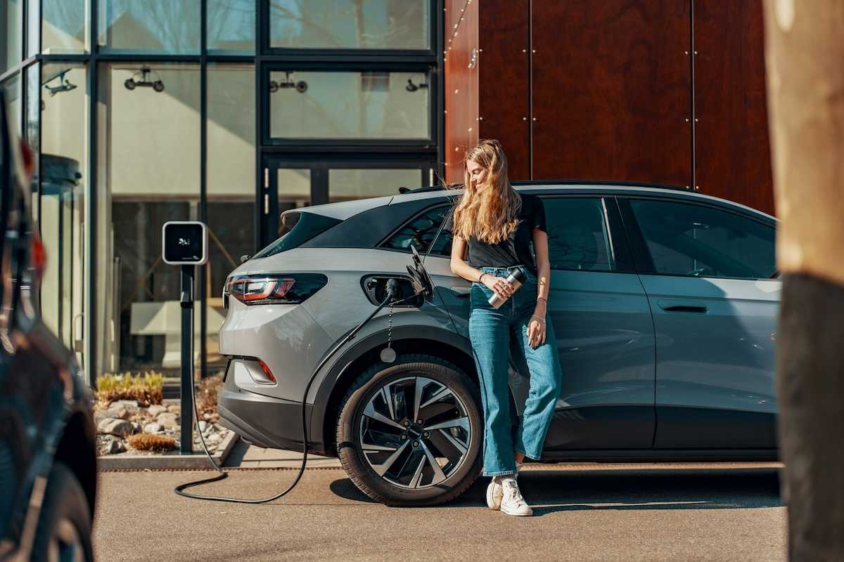 Woman dressed in blue jeans and black top casually charging an EV