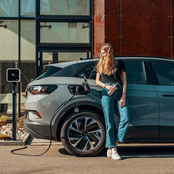 Woman dressed in blue jeans and black top casually charging an EV