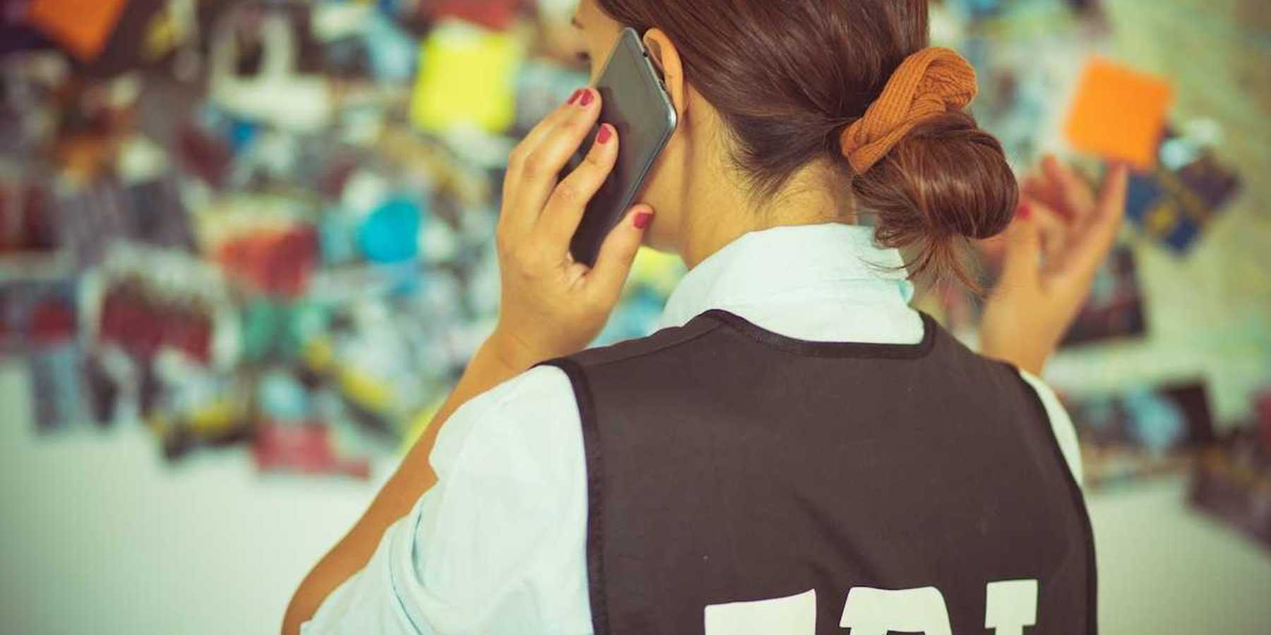 Woman FBI agent, back to camera, talking on the phone.