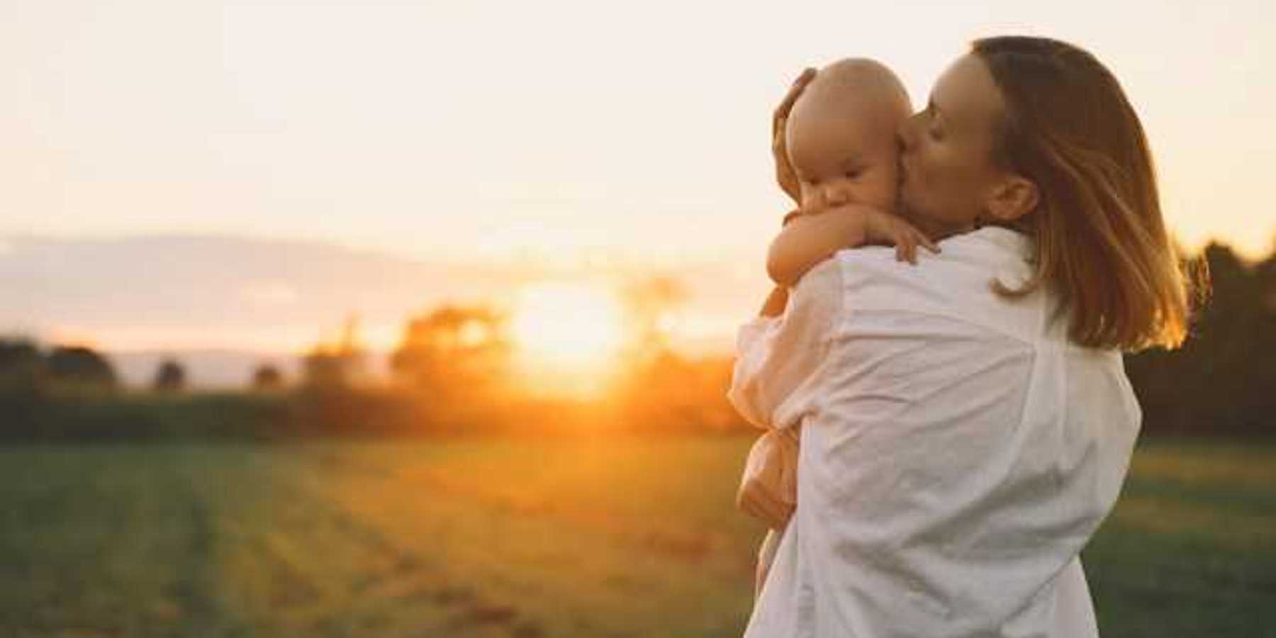 Woman holding a baby in a golden field