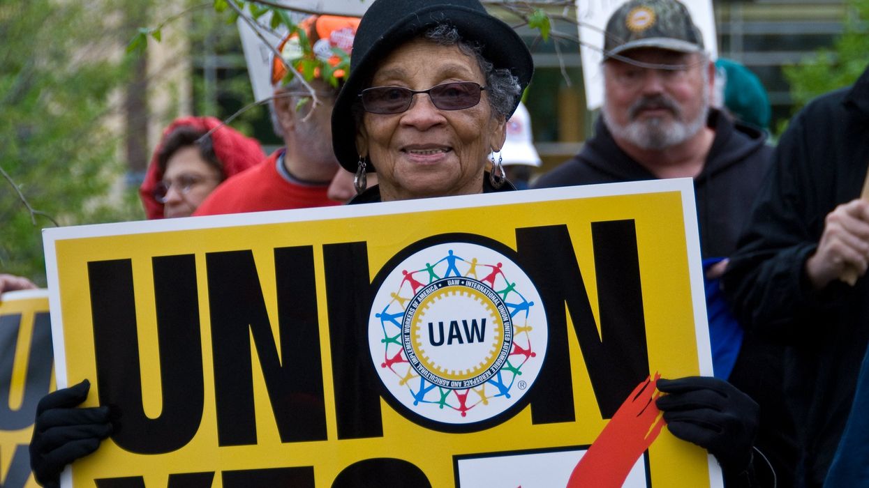 Woman holding a UAW "Union Yes" sign at a rally