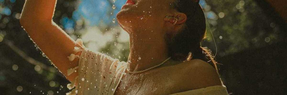 Woman in light clothing, cooling off by pouring water over herself.