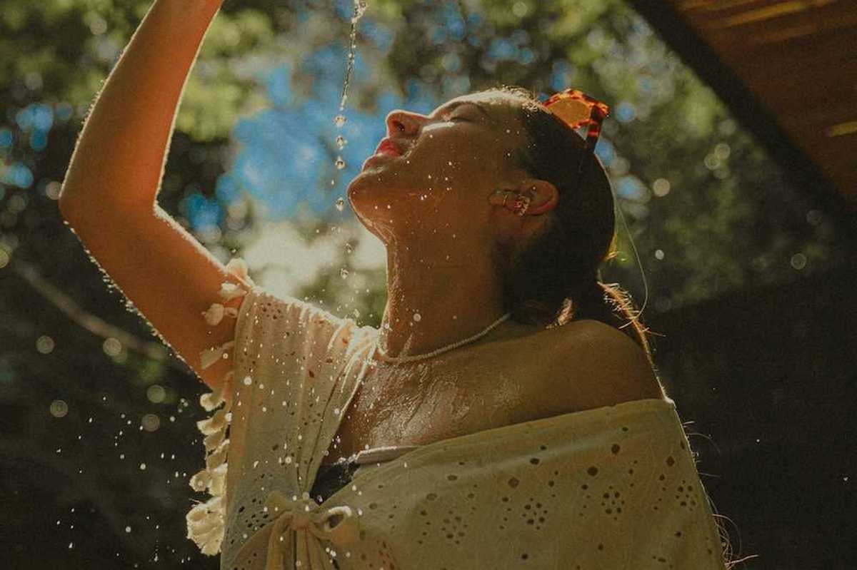 Woman in light clothing, cooling off by pouring water over herself.