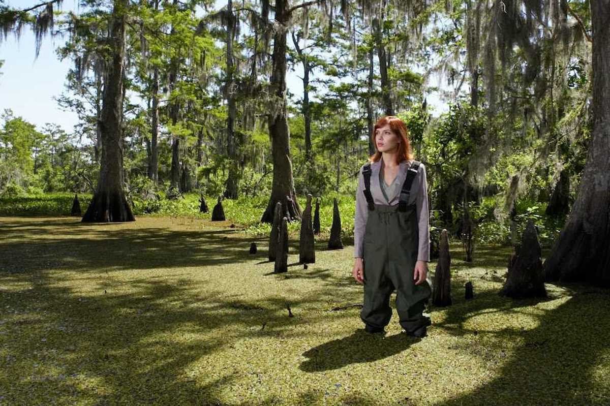 Woman in waders standing shin-deep in southeastern swamp