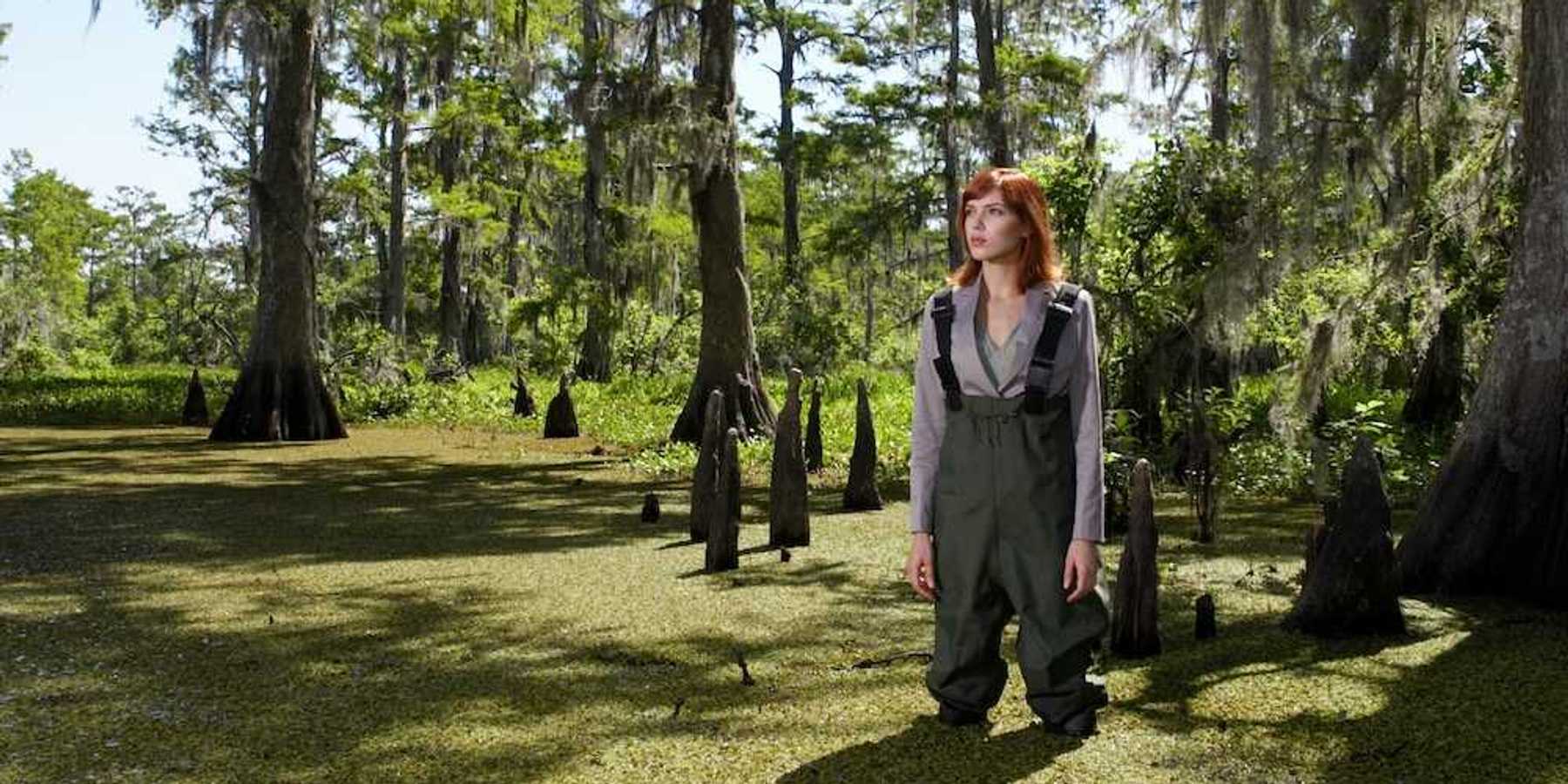 Woman in waders standing shin-deep in southeastern swamp