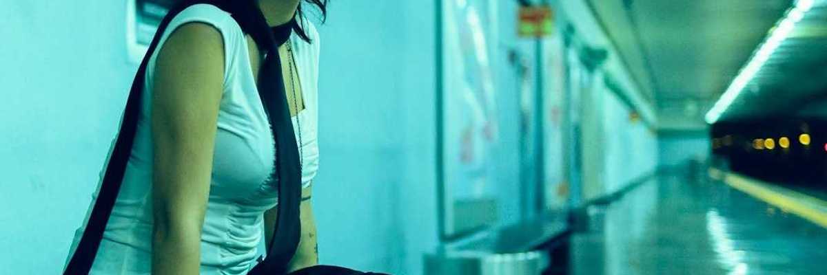 Woman seated on bench in underground station, waiting for subway for train