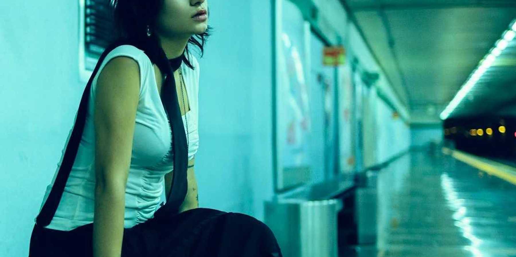 Woman seated on bench in underground station, waiting for subway for train