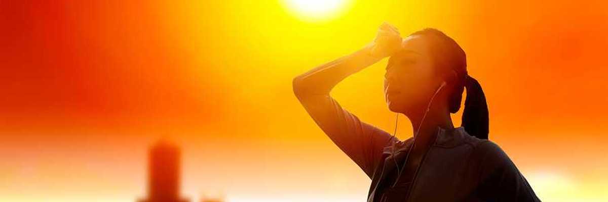 Woman shielding her eyes from sun with summer heat wave in the city background.
