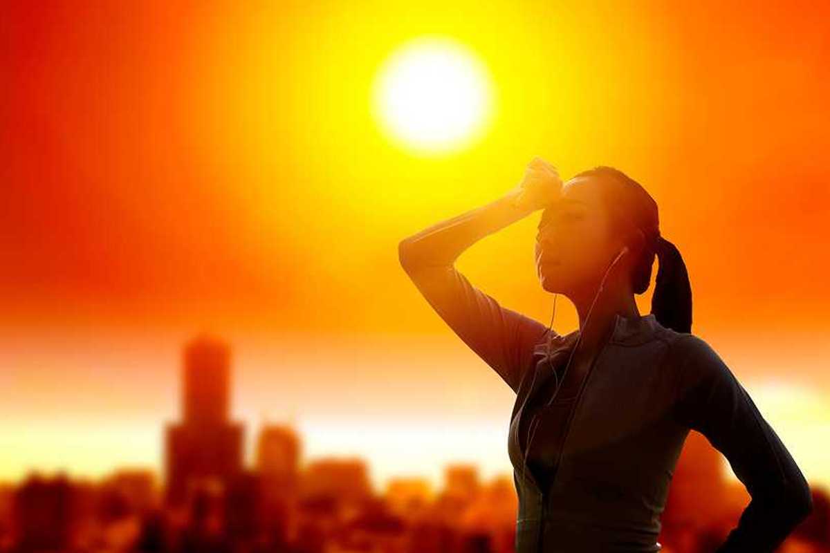 Woman shielding her eyes from sun with summer heat wave in the city background.
