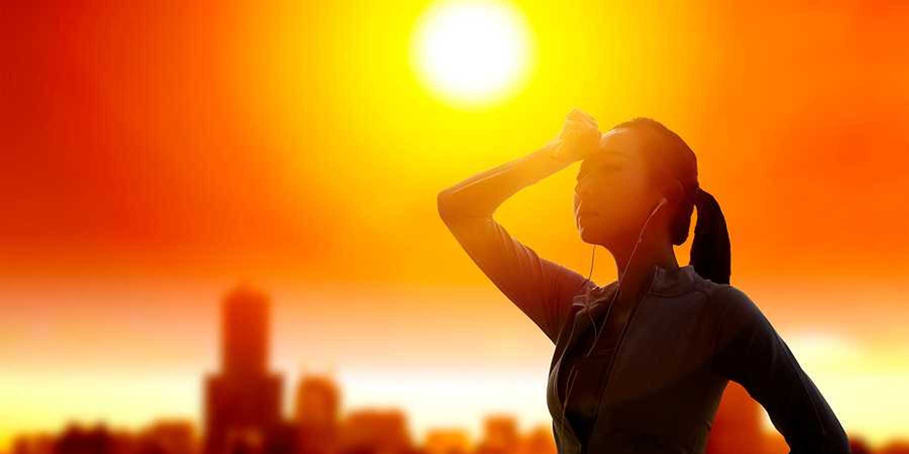 Woman shielding her eyes from sun with summer heat wave in the city background.