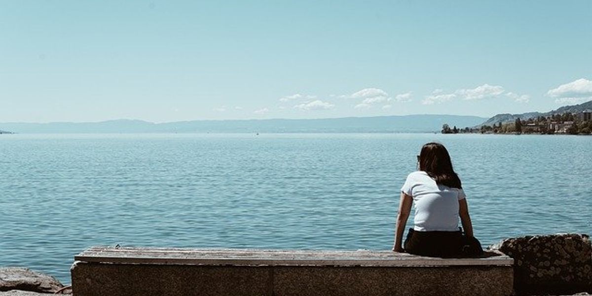 woman sitting on a bench looking out to sea