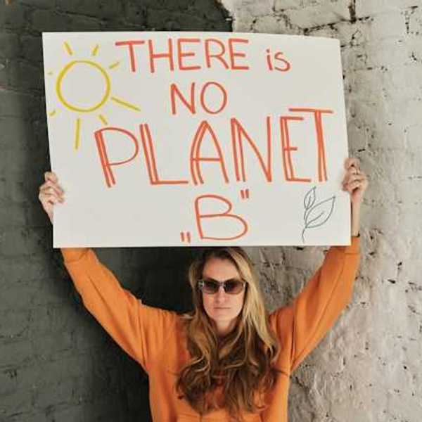 Woman wearing an orange sweatshirt holding a sign saying "There is no planet B"