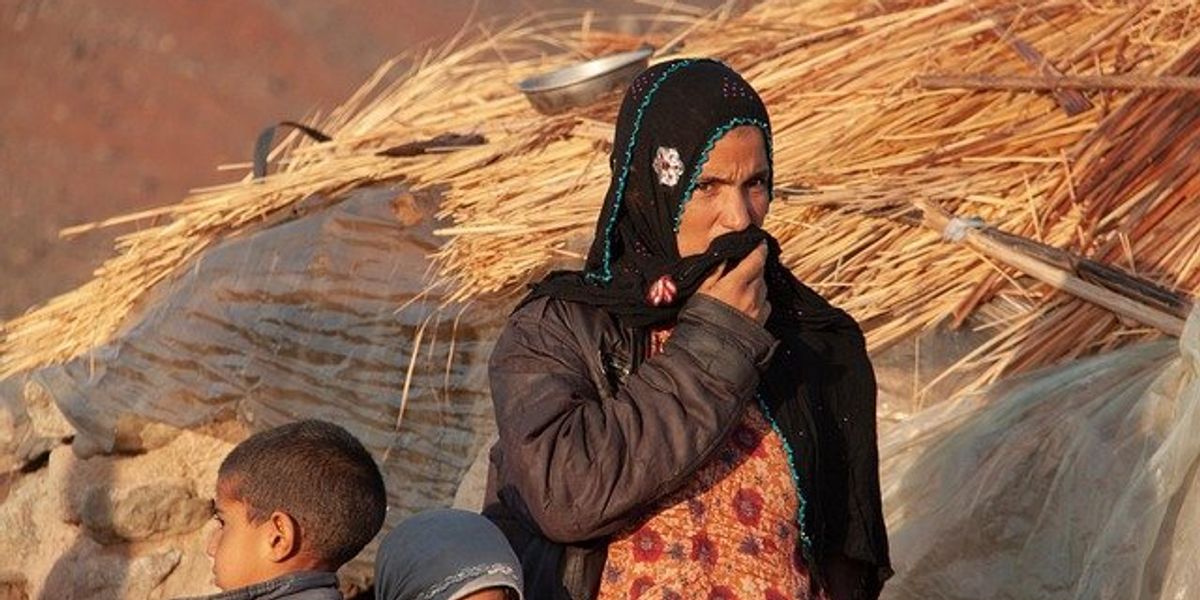 Woman wearing headscarf with two small children.