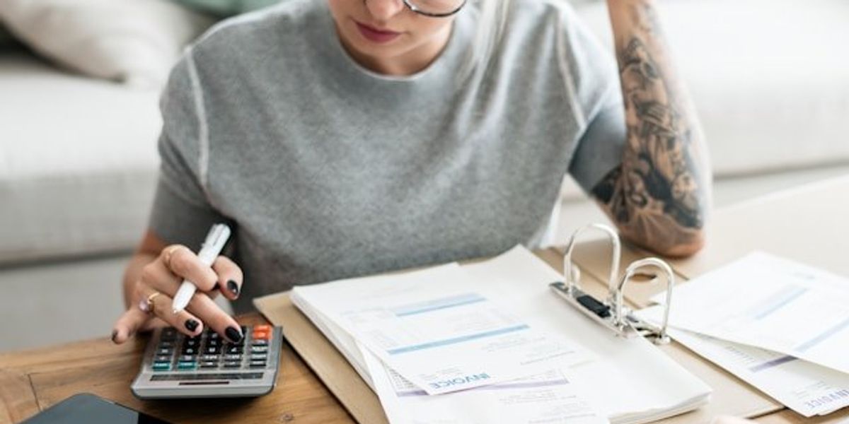 Woman with calculator looking at bills.