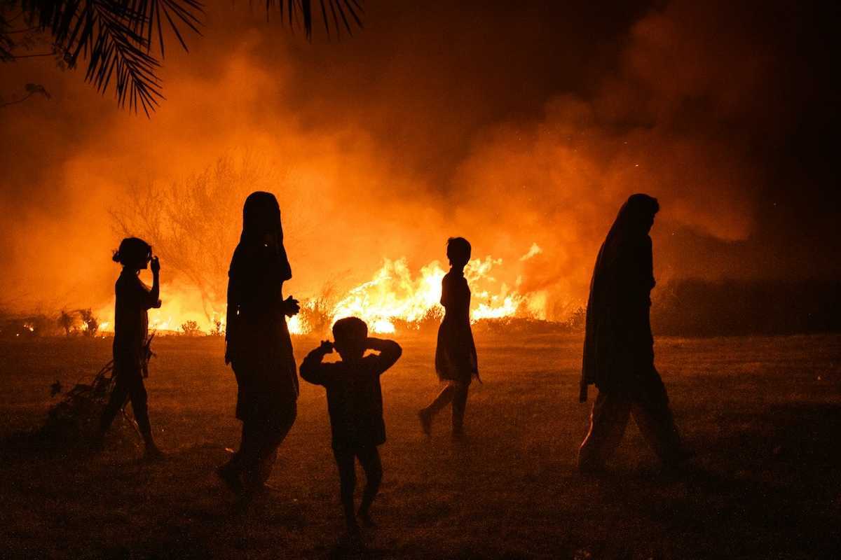 Women and children silhouetted against fire
