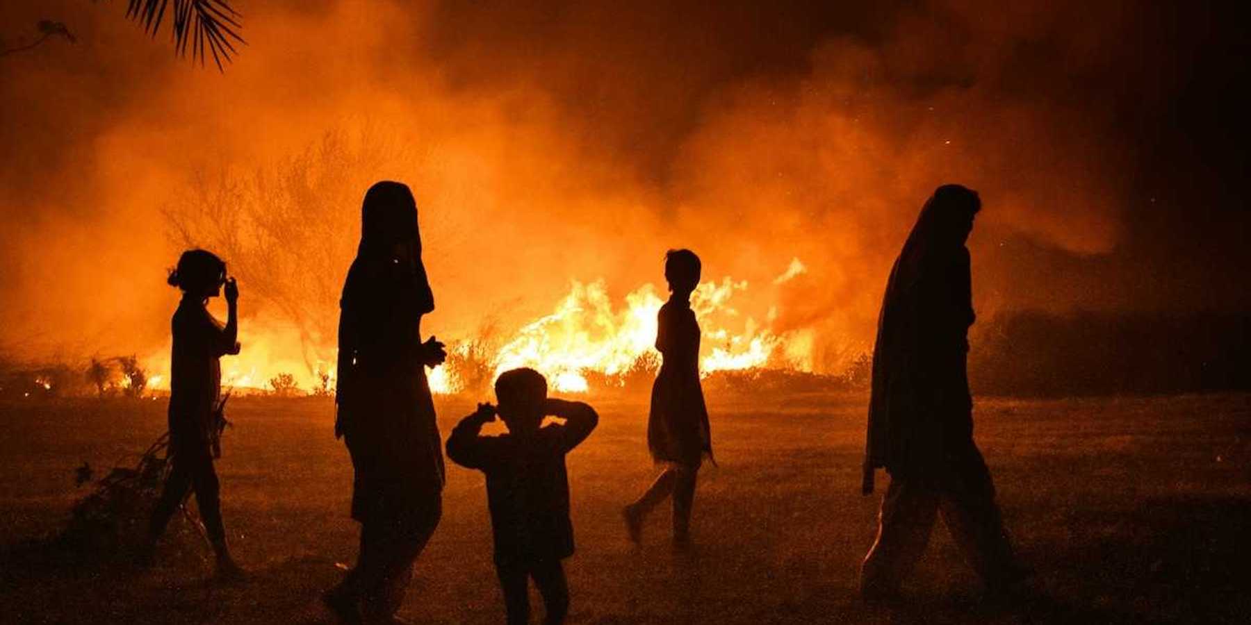Women and children silhouetted against fire
