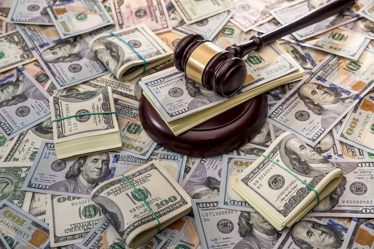 Wooden court gavel overlaying and surrounded by hundred-dollar bills