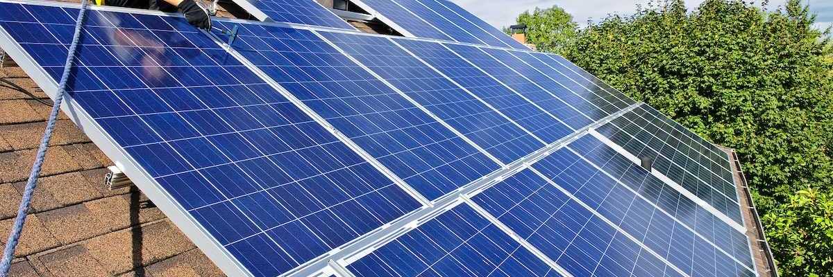 Worker installing solar panels on a shingled residential rooftop