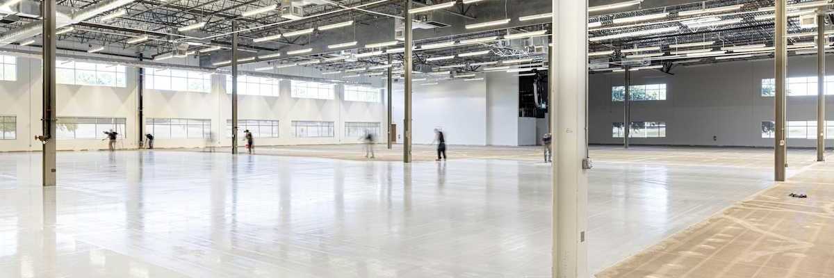 Workers finishing a concrete floor in an under-construction industrial space