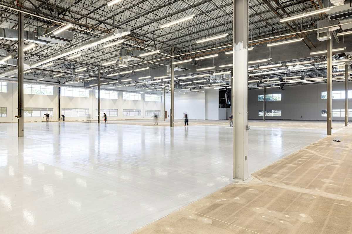 Workers finishing a concrete floor in an under-construction industrial space