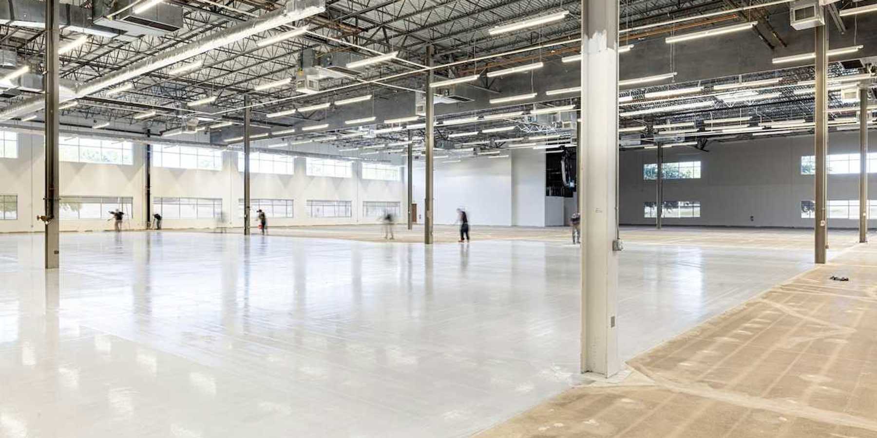 Workers finishing a concrete floor in an under-construction industrial space