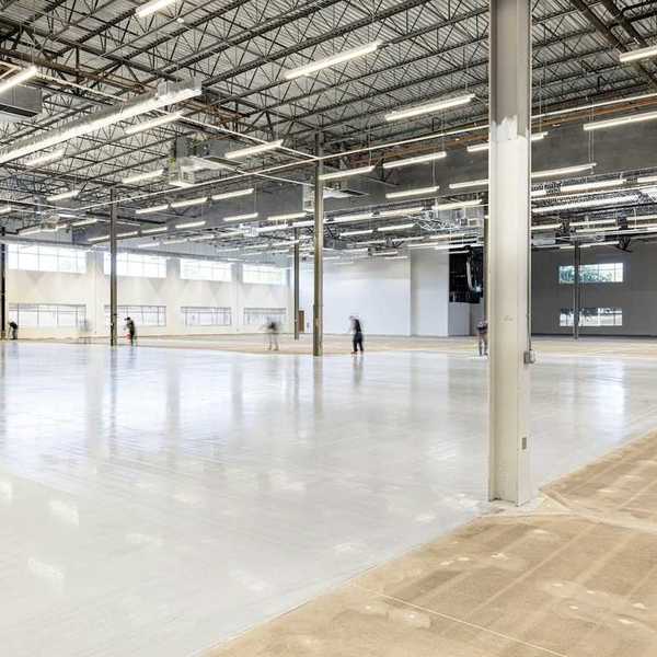 Workers finishing a concrete floor in an under-construction industrial space