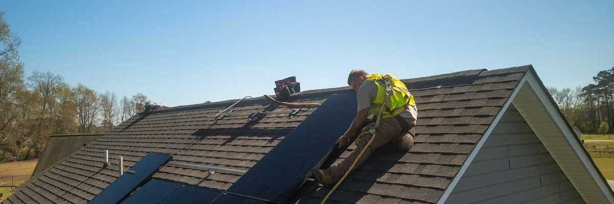 Workman installing solar panels on a residential roof