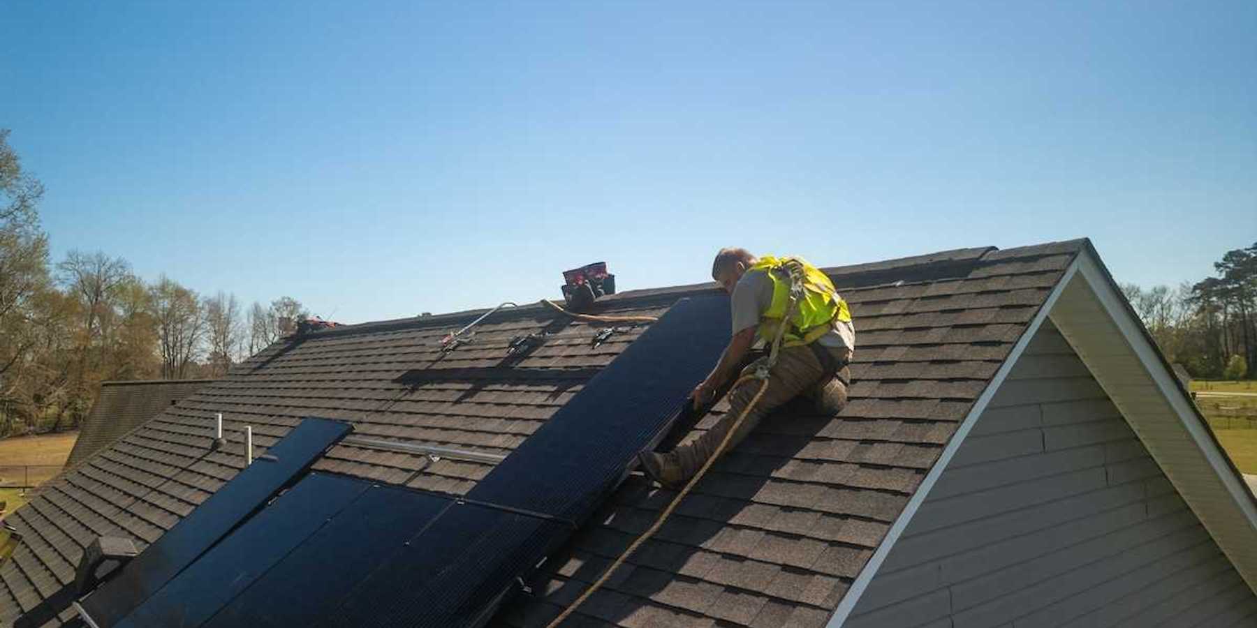 Workman installing solar panels on a residential roof