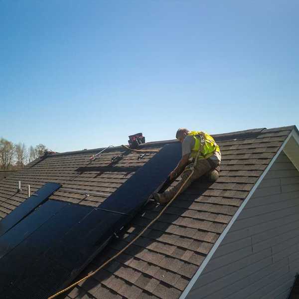 Workman installing solar panels on a residential roof