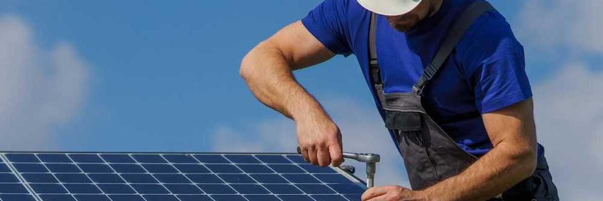 Workman securing a rooftop solar panel with a ratchet and socket wrench