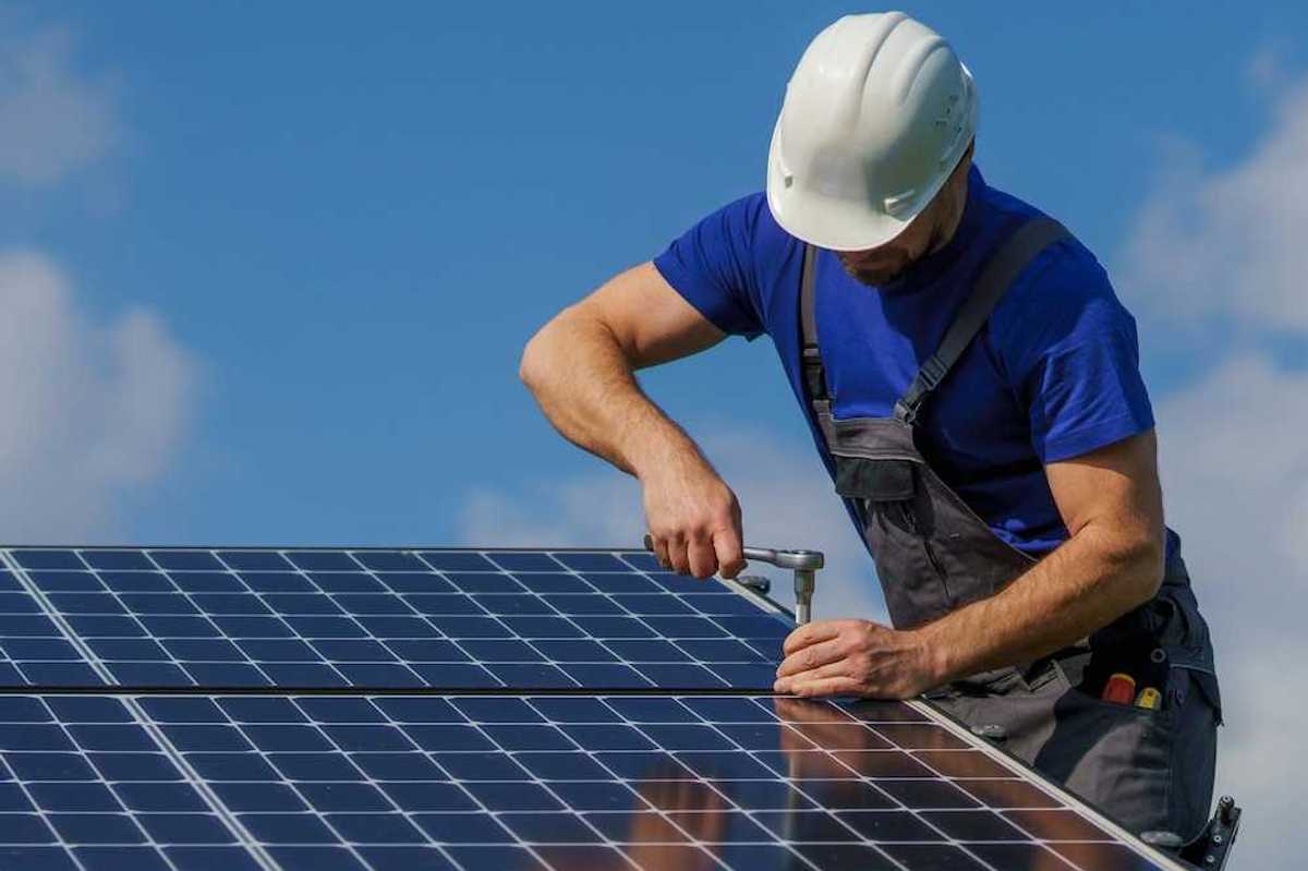 Workman securing a rooftop solar panel with a ratchet and socket wrench