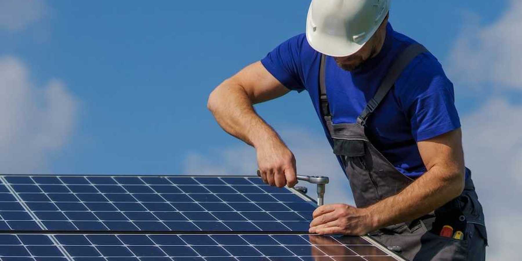 Workman securing a rooftop solar panel with a ratchet and socket wrench