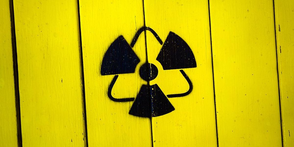 Yellow fence with a radioactive symbol painted on it.