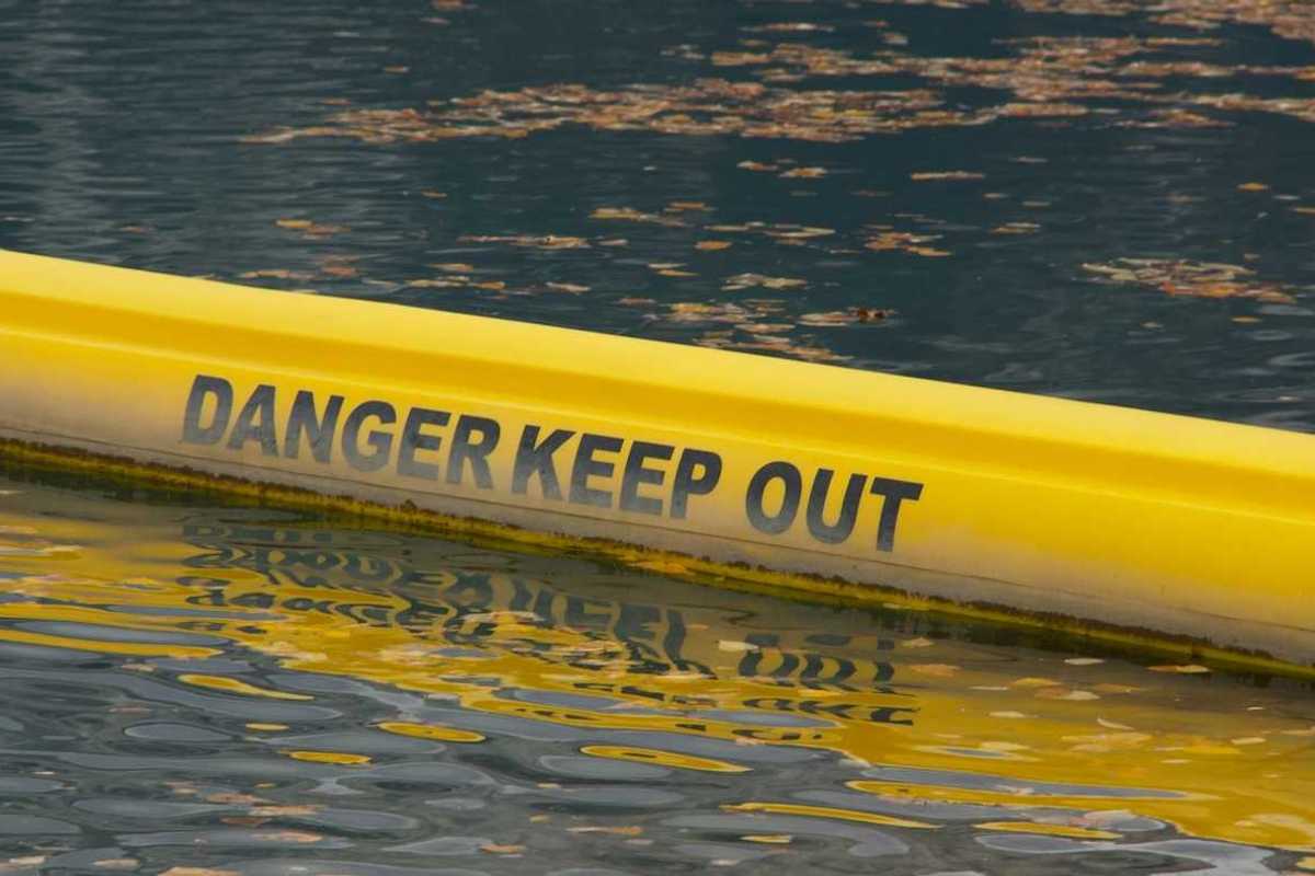 Yellow floating water barrier reading "DANGER KEEP OUT"